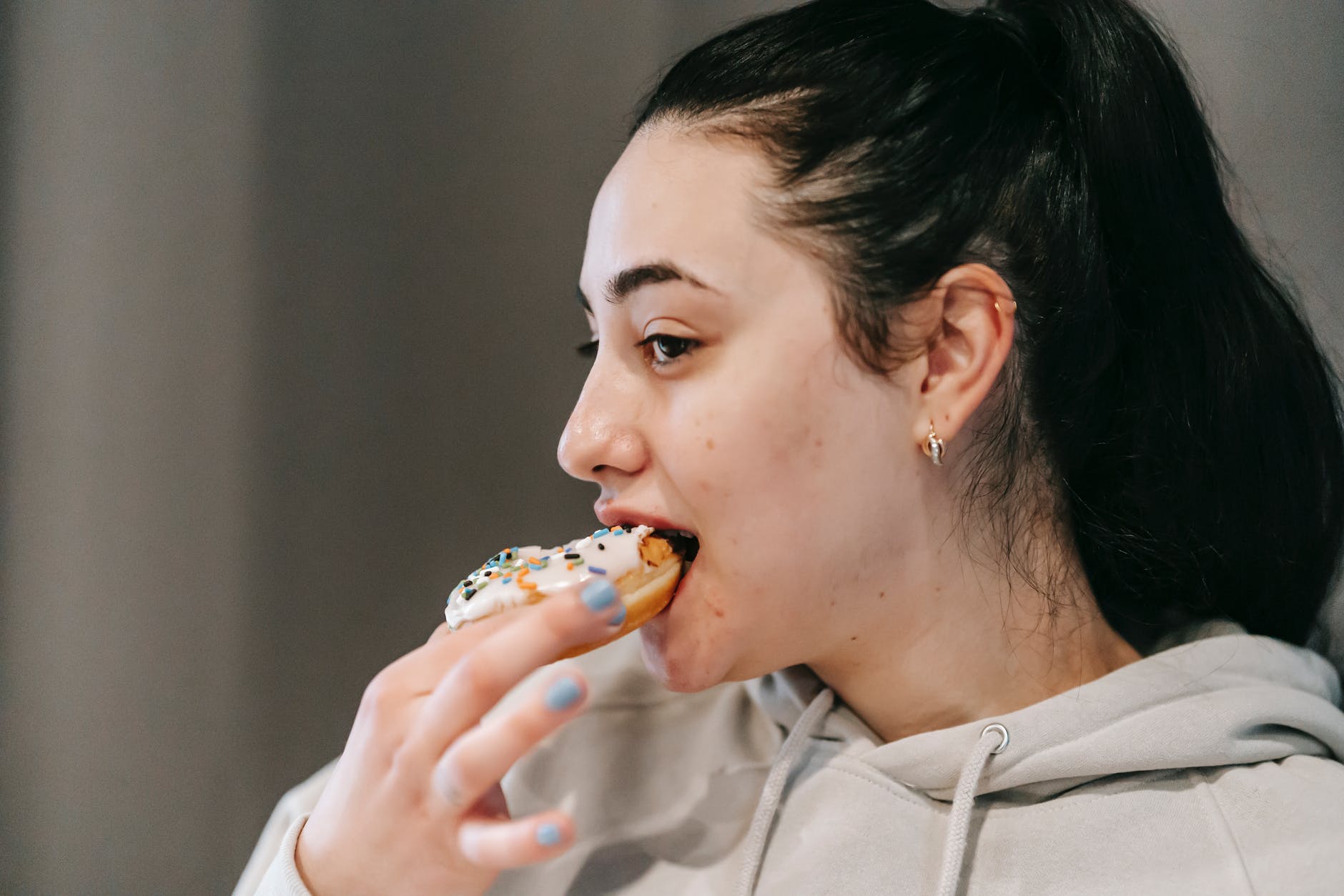 crop content woman biting sweet doughnut